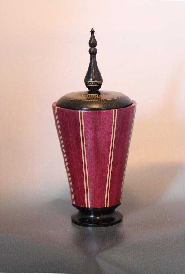 This piece is made from Purpleheart, Maple veneers and African Blackwood.  Using a staved construction it is 180mm tall and 64 mm at the widest part.Ther is also an applied gilded decoration on the lid.